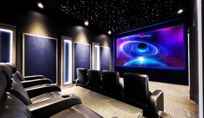 a home theater room with dark walls and a large screen.