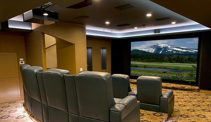 Smart luxury home theater with leather recliners and a large screen displaying a mountain view