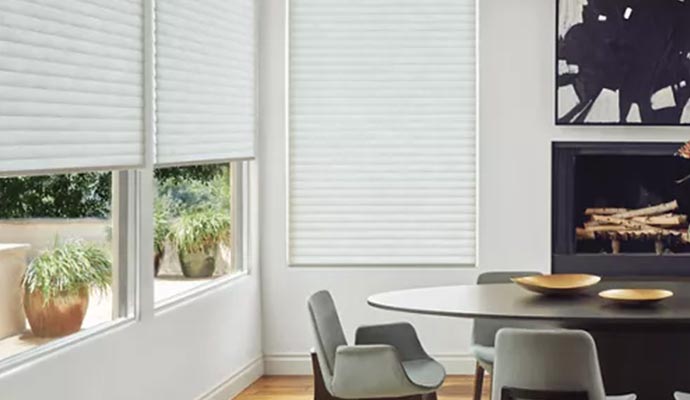 Modern dining room with large windows covered by white blinds