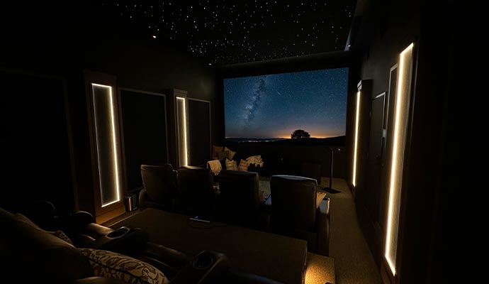 Luxury home theater featuring reclining seats and a large screen displaying a starry night sky