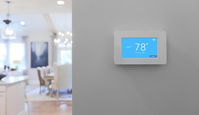 Smart home thermostat mounted on wall showing temperature and humidity in a modern home