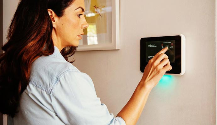 Woman using wall mounted home security touchscreen panel